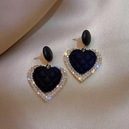 Gold earrings in the shape of dark hearts